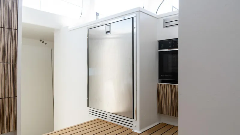 Slide: The Image of Modern kitchen interior on 2022 Custom Current Marine 46 yacht, featuring sleek appliances and wood accents. - 28