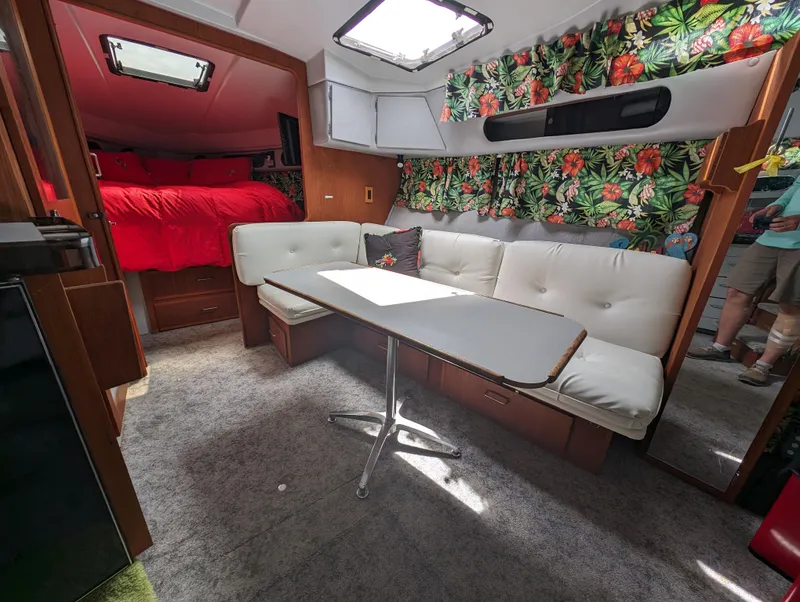 Slide: The Image of Interior of 1987 Cruisers 3370 Esprit with floral curtains, white seating, and dining table. - 2