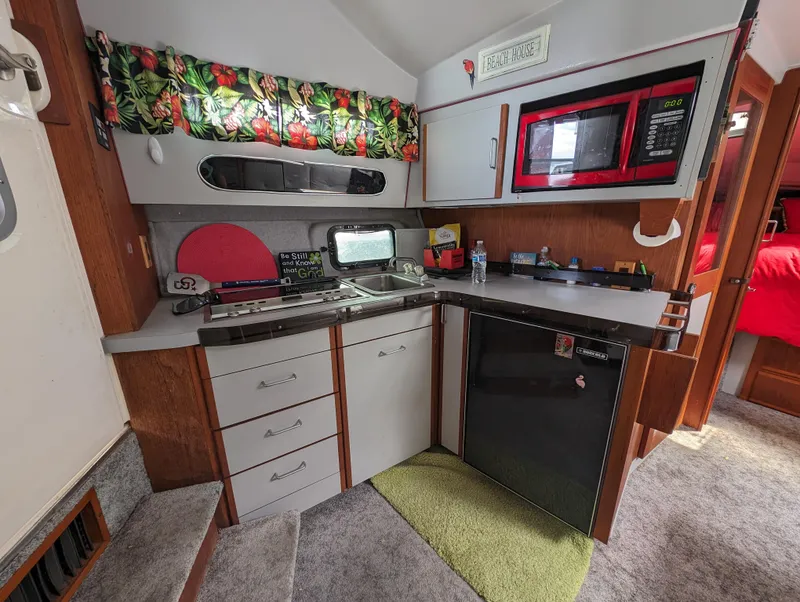 Slide: The Image of 1987 Cruisers 3370 Esprit boat kitchen with microwave, fridge, and tropical curtains. - 4