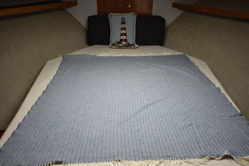 Slide: The Image of Cabo 35 Flybridge Sportfisher 1994 cabin bed with blue blanket and lighthouse pillow. - 44