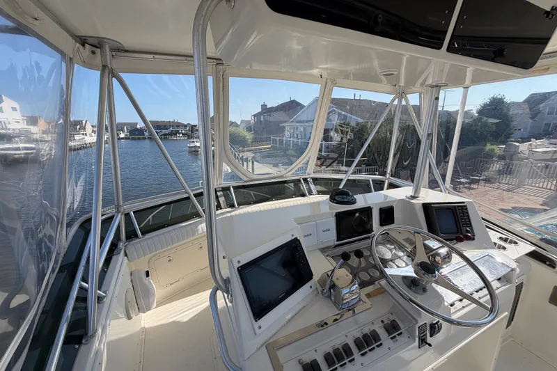 Slide: The Image of 1994 Cabo 35 Flybridge helm with navigational equipment, overlooking a serene waterfront view. - 76