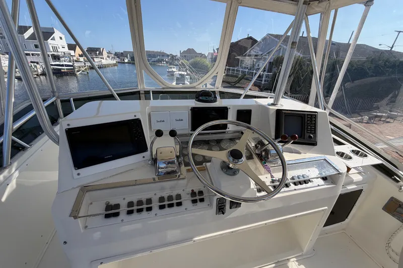 Slide: The Image of Helm of 1994 Cabo 35 Flybridge boat with navigational equipment and waterfront view. - 75