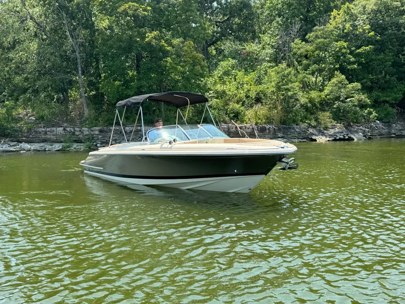 Slide: The Image of 2019 Chris-Craft Launch 27 boat cruising on a serene lake with lush greenery. - 2