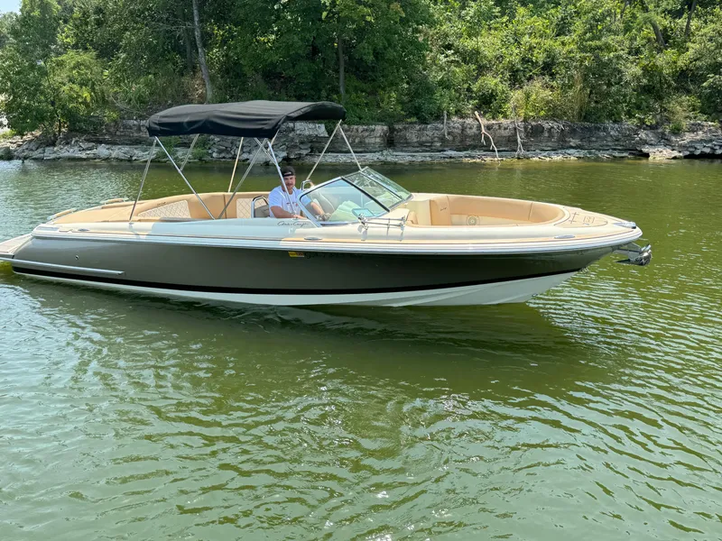 Slide: The Image of 2019 Chris-Craft Launch 27 boat cruising on a serene lake with lush greenery. - 3