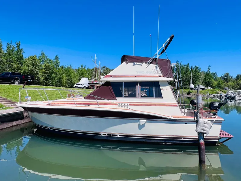 Slide: The Image of 1982 Trojan F32 boat docked in a serene marina under a clear blue sky. - 2