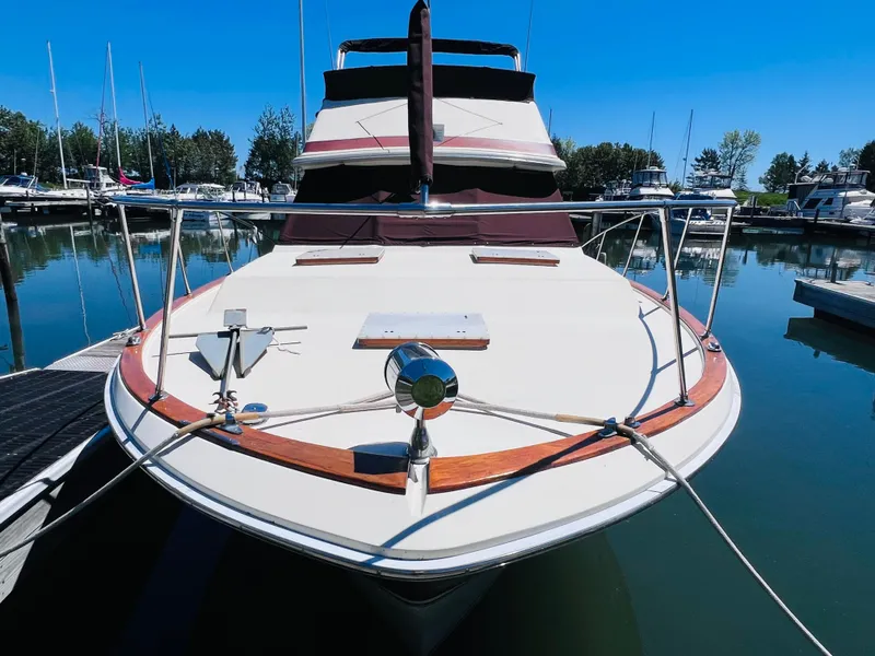 Slide: The Image of 1982 Trojan F32 boat docked in a marina, clear blue sky, calm water. - 3