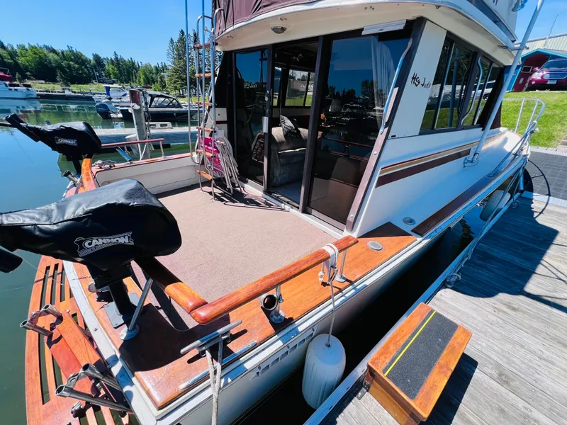 Slide: The Image of 1982 Trojan F32 boat docked, featuring a spacious deck and covered equipment, in a serene marina setting. - 4