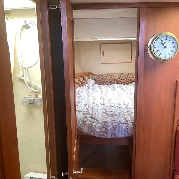 Slide: The Image of 1982 Trojan F32 cabin interior with bed, clock, and wooden paneling. - 11