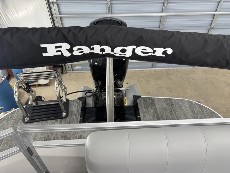Slide: The Image of 2024 Ranger 220C boat interior with branded cover and ladder in a garage setting. - 6