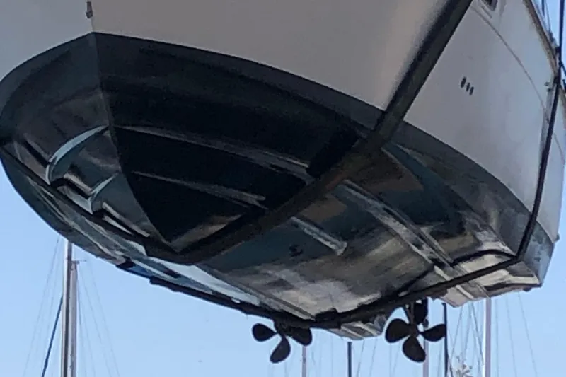 Slide: The Image of 1988 Cruisers Esprit 2980 boat hull with visible propellers, suspended for maintenance. - 4