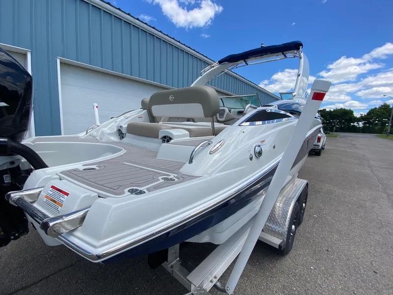 Slide: The Image of 2023 Crownline 280 XSS boat on trailer, parked near a blue building under a clear sky. - 12