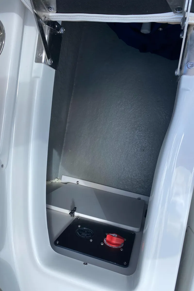 Slide: The Image of 2023 Crownline 280 XSS boat storage compartment with red control switch. - 27