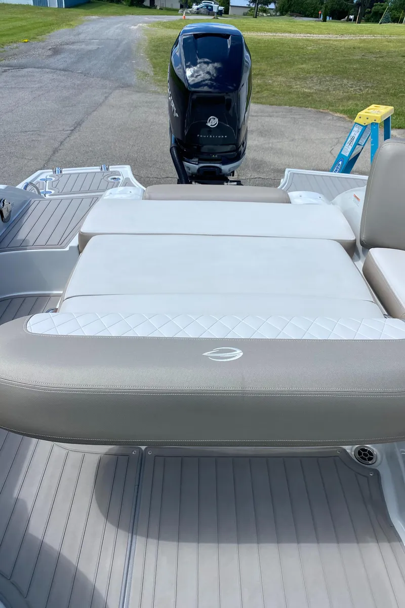 Slide: The Image of 2023 Crownline 280 XSS boat with beige seating and outboard motor, parked on pavement. - 29