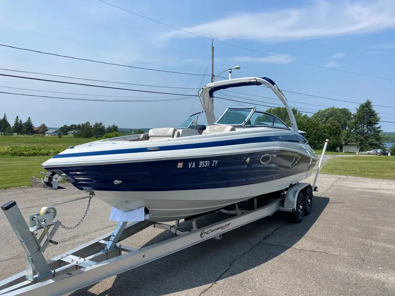 Slide: The Image of 2023 Crownline 280 XSS boat on trailer, parked outdoors under a clear sky. - 3
