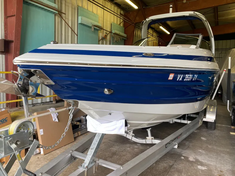 Slide: The Image of 2023 Crownline 280 XSS boat in storage, blue and white exterior, on a trailer. - 4