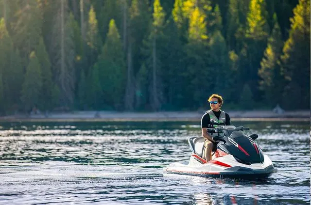 Slide: The Image of 2024 Kawasaki Waverunner Jet Ski STX speeding on a lake with scenic mountain backdrop. - 3