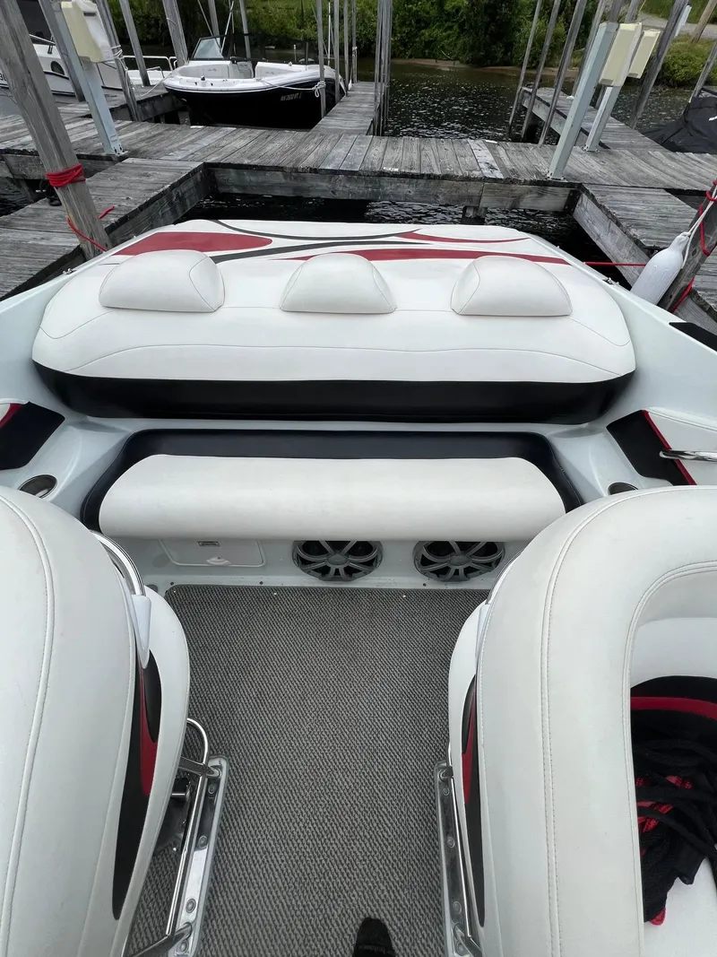 Slide: The Image of 2007 Baja Outlaw 260 boat interior with white and red seating at a dock. - 5