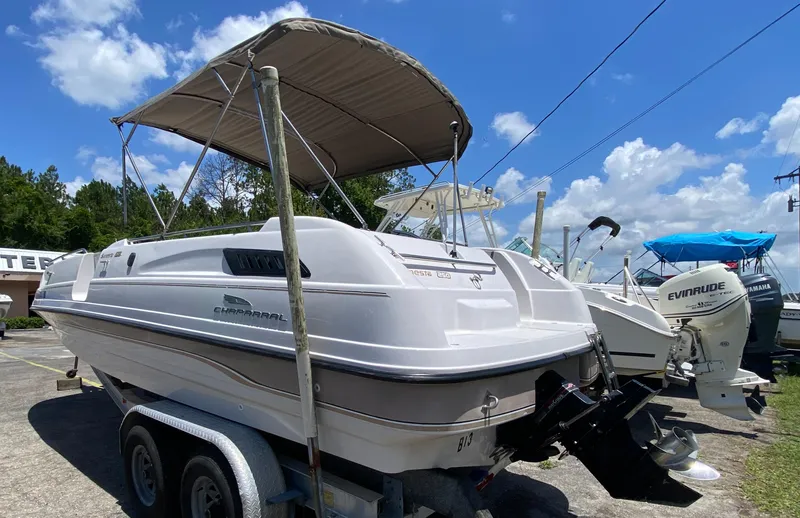 The Image of 1997 Chaparral 250 Sunseta boat on trailer, with canopy, parked outdoors. - 0