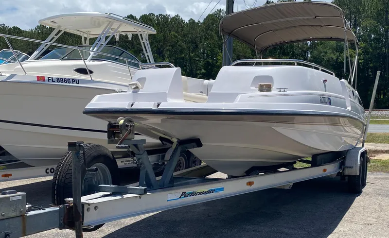 Slide: The Image of 1997 Chaparral 250 Sunseta boat on a trailer, parked next to another boat. - 1