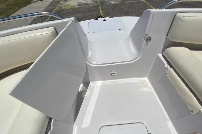 Slide: The Image of 1997 Chaparral 250 Sunseta boat interior with white seating and storage compartments. - 10