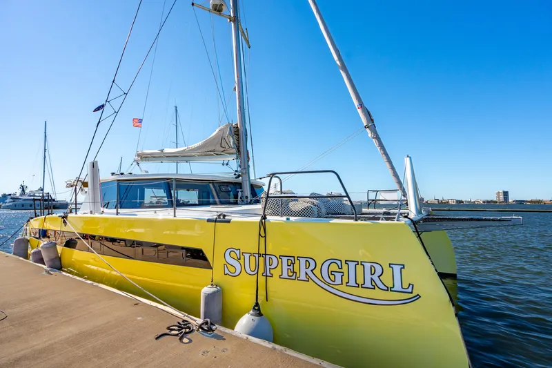 Slide: The Image of Yellow Balance 442 catamaran named "Supergirl" docked by the water, 2022 model. - 12