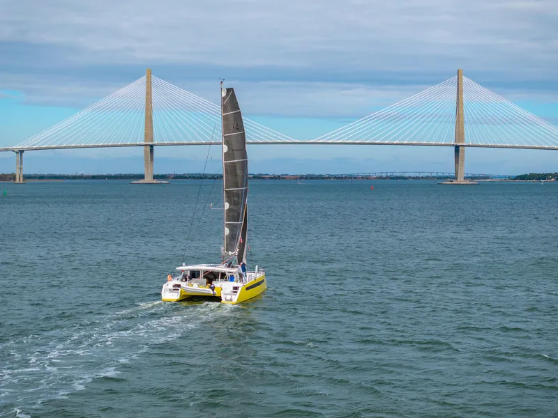 Slide: The Image of Yellow Balance 442 catamaran sailing near a large suspension bridge, 2022. - 2