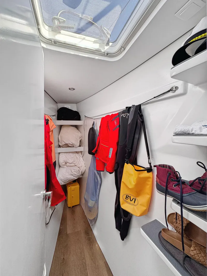 Slide: The Image of Narrow storage area in a 2022 Balance 442 boat with shelves and hanging gear. - 51