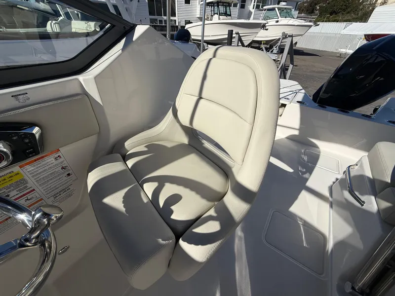 Slide: The Image of 2025 Boston Whaler 210 Vantage boat interior with beige seating and steering wheel. - 13