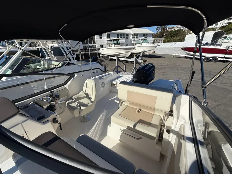 Slide: The Image of 2025 Boston Whaler 210 Vantage boat interior with seating and helm, docked outdoors. - 15