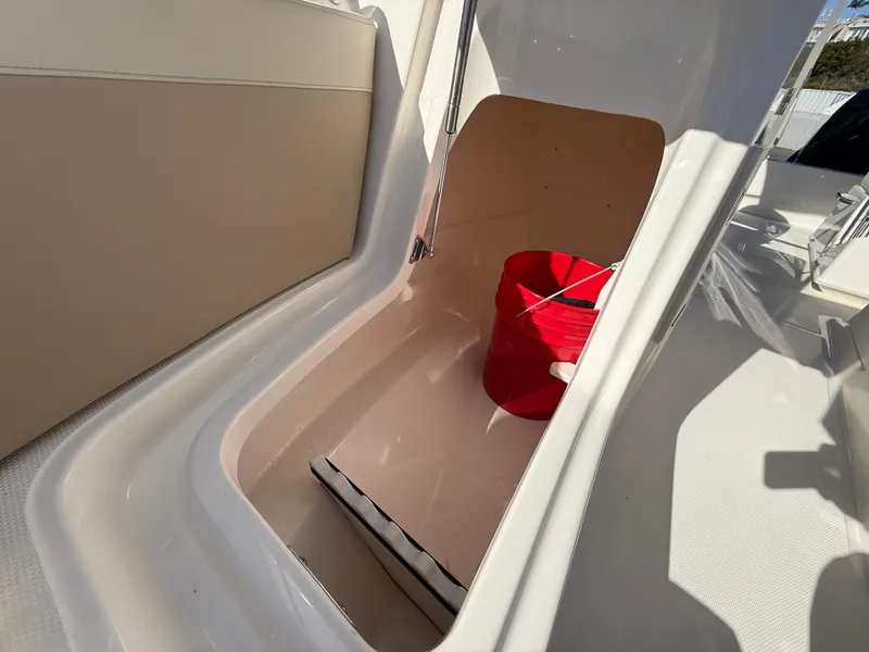 Slide: The Image of 2025 Boston Whaler 210 Vantage storage compartment with red bucket inside. - 17