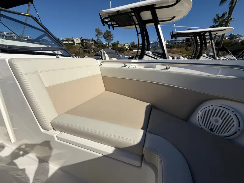Slide: The Image of 2025 Boston Whaler 210 Vantage boat interior seating with speaker, docked under clear blue sky. - 18