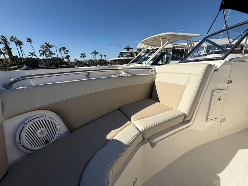 Slide: The Image of 2025 Boston Whaler 210 Vantage boat interior with beige seating and speaker, docked under clear sky. - 22