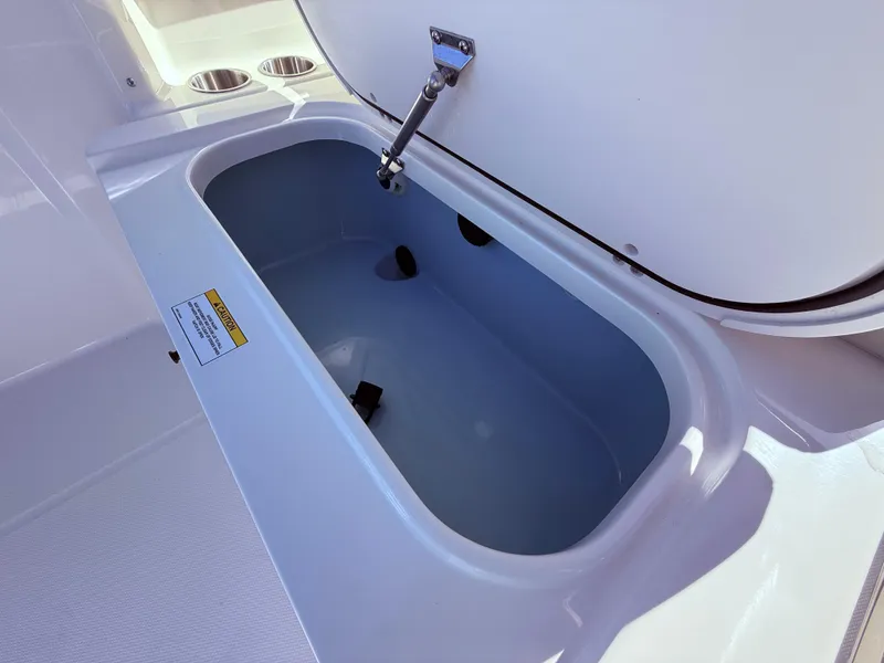 Slide: The Image of 2025 Boston Whaler 210 Vantage storage compartment, open lid, white interior. - 7