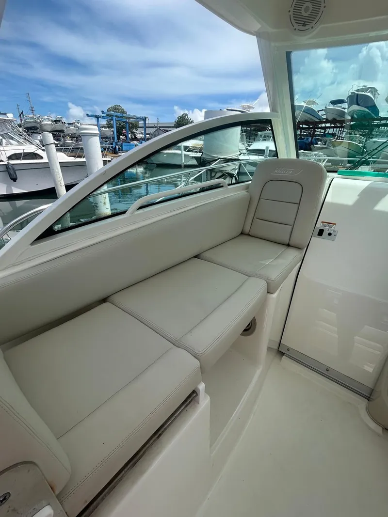 Slide: The Image of 2023 Boston Whaler 285 Conquest interior with beige seating, docked at marina. - 2