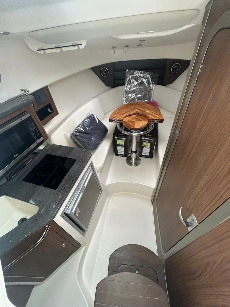 Slide: The Image of 2023 Boston Whaler 285 Conquest cabin interior with kitchenette and seating area. - 4