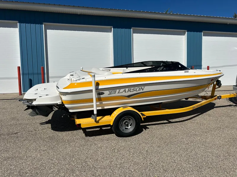 Slide: The Image of 2007 Larson 180SEI LX boat on trailer, parked outside blue storage units. - 2