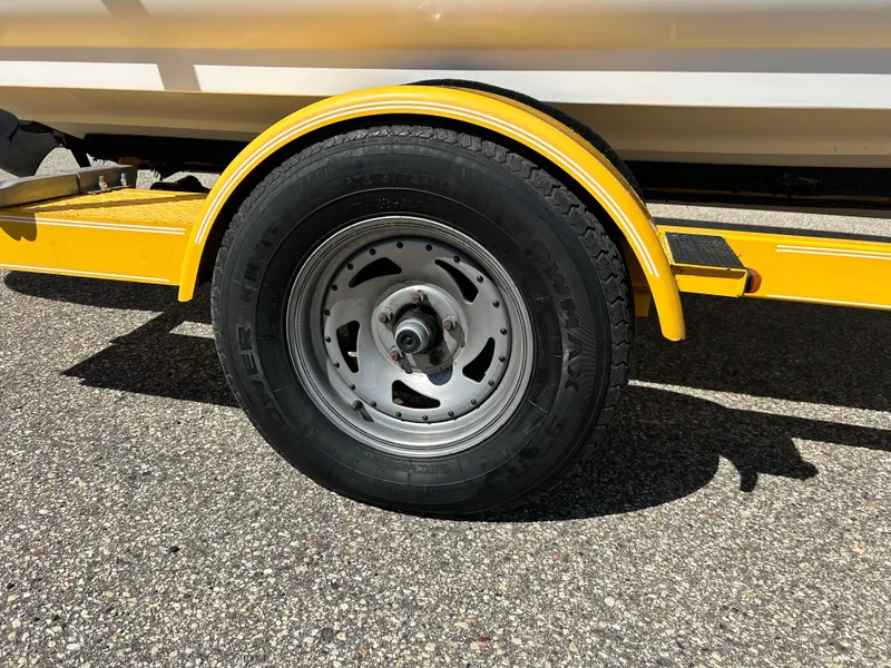 Slide: The Image of Yellow trailer wheel of a 2007 Larson 180SEI LX boat on asphalt. - 4
