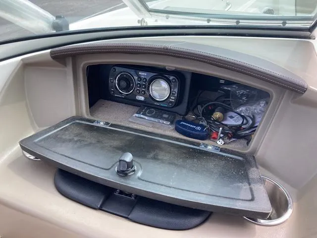 Slide: The Image of 2011 Sea Ray 230 SLX boat dashboard with Sony stereo and storage compartment. - 14