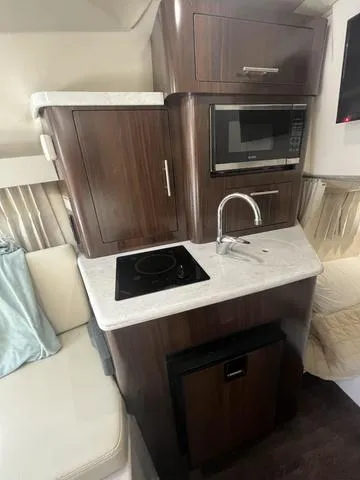 Slide: The Image of 2019 Regal 28 Express boat interior kitchen with microwave, sink, and stove. - 22