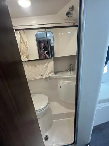 Slide: The Image of 2019 Regal 28 Express boat bathroom with toilet, sink, and mirror. - 25