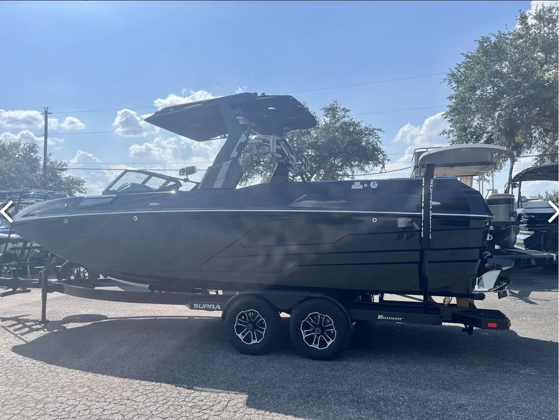 Slide: The Image of 2024 Supra SE 550 boat on trailer under sunny sky. - 1