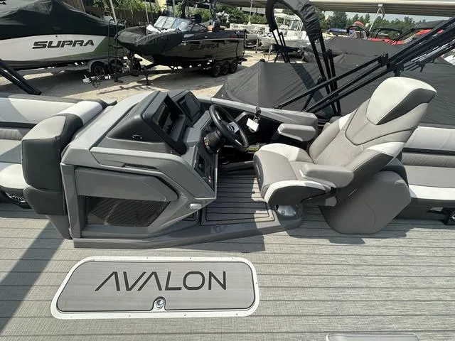 Slide: The Image of 2024 Avalon Catalina 25' Quad Lounger boat interior with captain's chair and control console. - 24