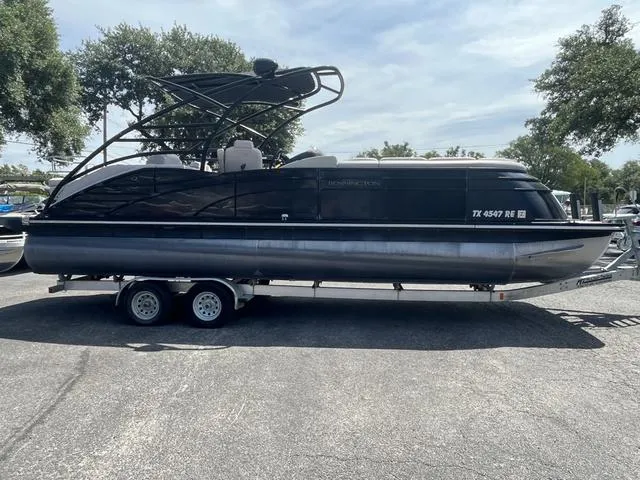 Slide: The Image of 2015 Bennington 25 IO QCW pontoon boat on a trailer in a parking lot. - 1