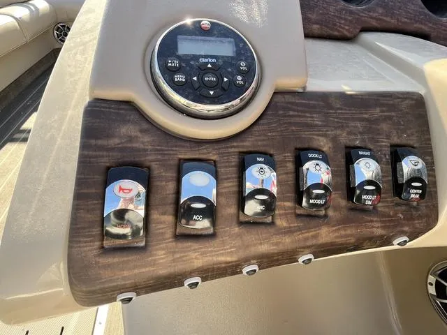 Slide: The Image of Control panel of a 2015 Bennington 2275 RCW boat with various switches and a Clarion stereo. - 9