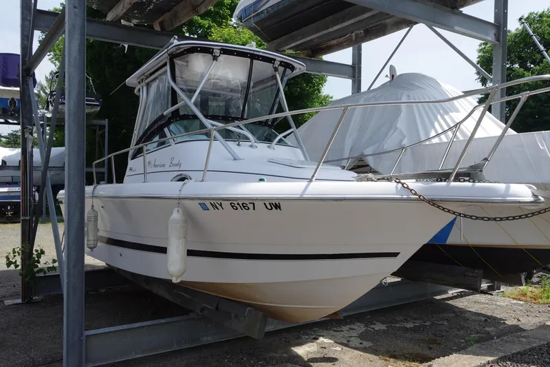 The Image of 2000 Pro-Line 24 Walk boat on storage rack, white hull, outdoor setting. - 0