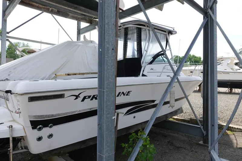 Slide: The Image of 2000 Pro-Line 24 Walk boat in storage, partially covered, with visible branding. - 1