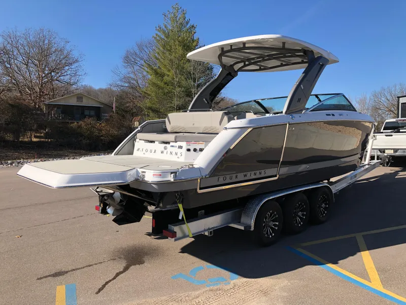 Slide: The Image of 2025 Four Winns H9 boat on trailer, parked outdoors on a sunny day. - 10