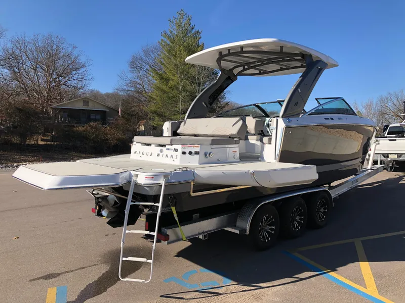 Slide: The Image of 2025 Four Winns H9 boat on trailer, parked outdoors under clear blue sky. - 27