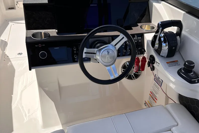 Slide: The Image of 2021 Sea Ray SDX 290 Outboard helm with steering wheel, controls, and cup holders. - 7