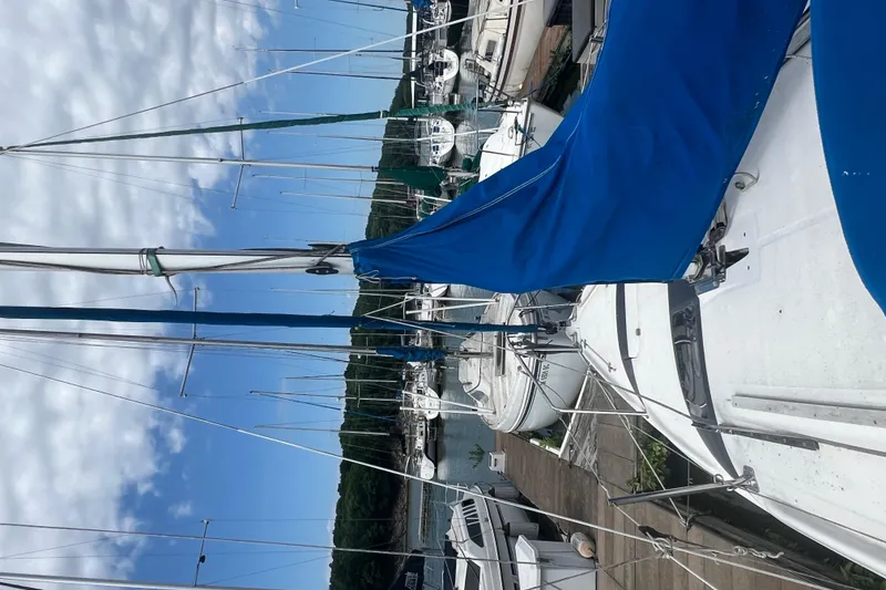 Slide: The Image of 2010 MacGregor 26M sailboat docked at a marina with blue sail cover. - 10